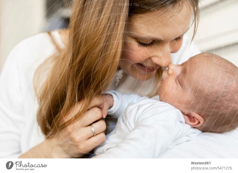 Nahaufnahme einer lächelnden Mutter, die sich mit einem schlafenden Jungen zu Hause die Nase reibt Farbaufnahme Farbe Farbfoto Farbphoto Innenaufnahme