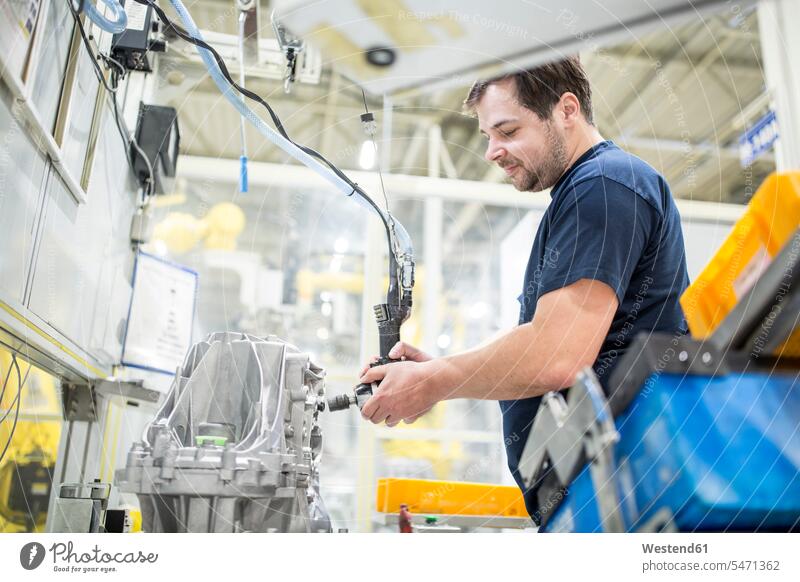 Mann arbeitet in einer modernen Fabrik Job Berufe Berufstätigkeit Beschäftigung Jobs Arbeiter T-Shirts Geräte Werkzeuge stehend steht Arbeitsstätte Arbeitstelle