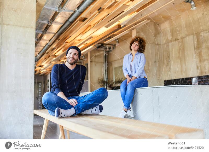 Frau und Mann entspannen im modernen Büro Deutschland Pausenraum Beanie Beanies Work-Life-Balance Businessmann Seitenblick Blick zur Seite Freiberufler