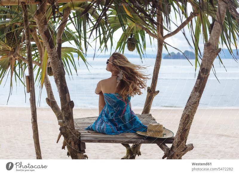 Junge sitzende Frau am Strand, die auf das Meer schaut Beach Straende Strände Beaches junge Frau junge Frauen Meere Urlaub Ferien sitzt weiblich Erwachsener