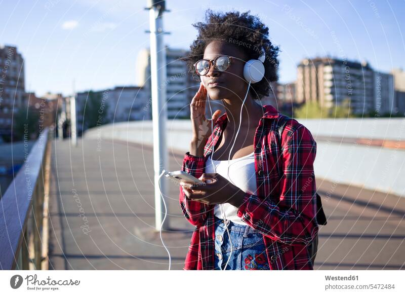 Porträt einer jungen Frau auf einer Brücke, die mit Kopfhörern Musik hört Kopfhoerer weiblich Frauen Portrait Porträts Portraits hören hoeren Bruecken Brücken