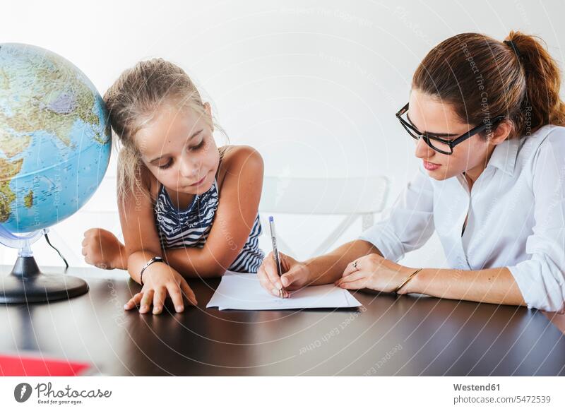 Lehrer hilft Schulmädchen am Schreibtisch schreiben auf Papier Leute Menschen People Person Personen Europäisch Kaukasier kaukasisch 2 2 Menschen 2 Personen