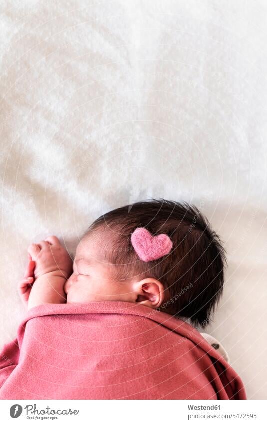 Neugeborenes Mädchen mit Herzform auf dem Kopf schläft über Bett im Krankenhaus Farbaufnahme Farbe Farbfoto Farbphoto Spanien Innenaufnahme Innenaufnahmen innen