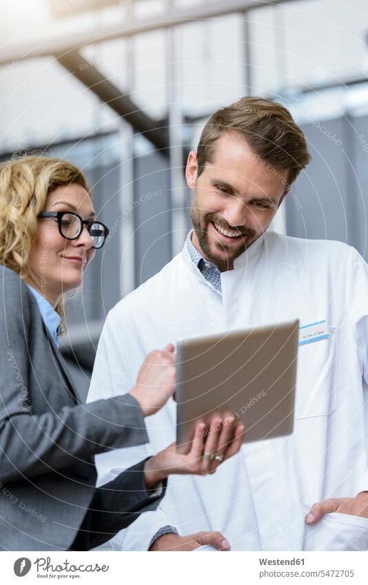 Geschäftsfrau mit Tablette und glücklichem Arzt im Krankenhaus Job Berufe Berufstätigkeit Beschäftigung Jobs geschäftlich Geschäftsleben Geschäftswelt