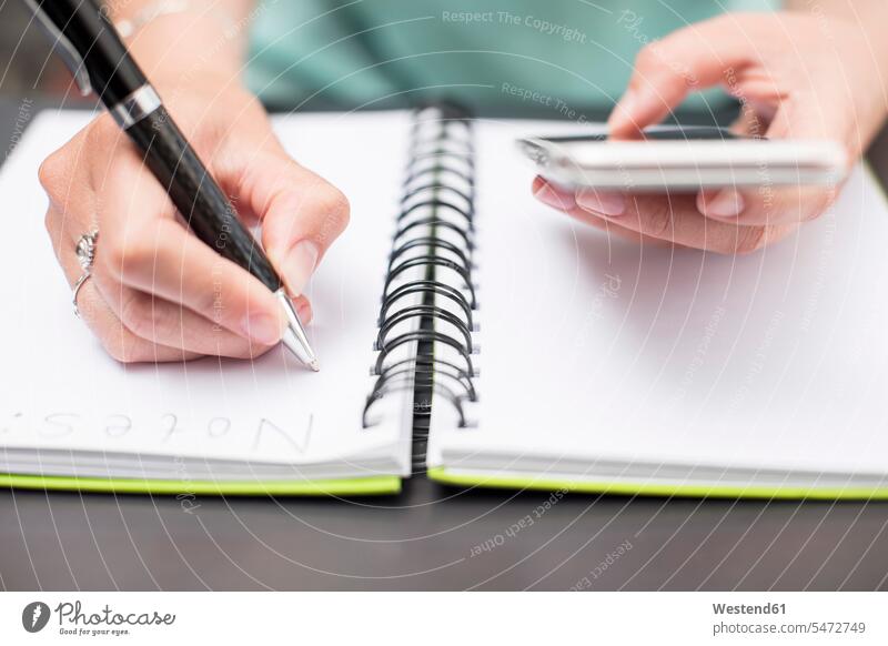 Frau schreibt Notizen in Tagebuch, hält Smartphone Termin Termine iPhone Smartphones Organisation Organisieren Kugelschreiber Kuli Kulis schreiben aufschreiben