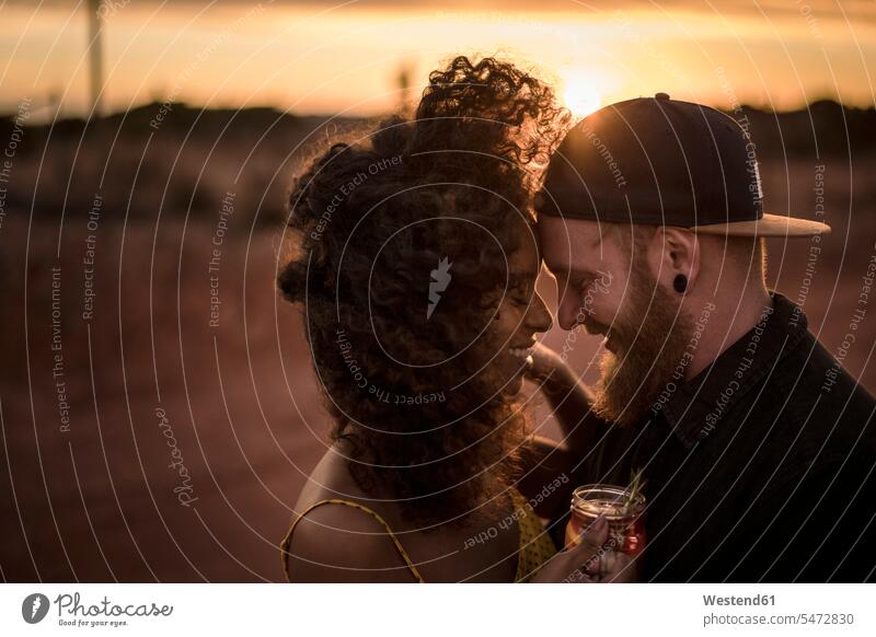 Glückliches Paar trinkt bei Sonnenuntergang im Freien frischen Eistee Touristen Leute Menschen People Person Personen gelockt gelockte Haare gelocktes Haar