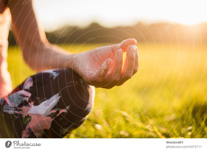 Detail der Frau im Lotussitz auf ländlicher Wiese bei Sonnenuntergang auf dem Land auf dem Lande Sonnenuntergänge weiblich Frauen Yoga Yoga-Übungen Yogauebungen