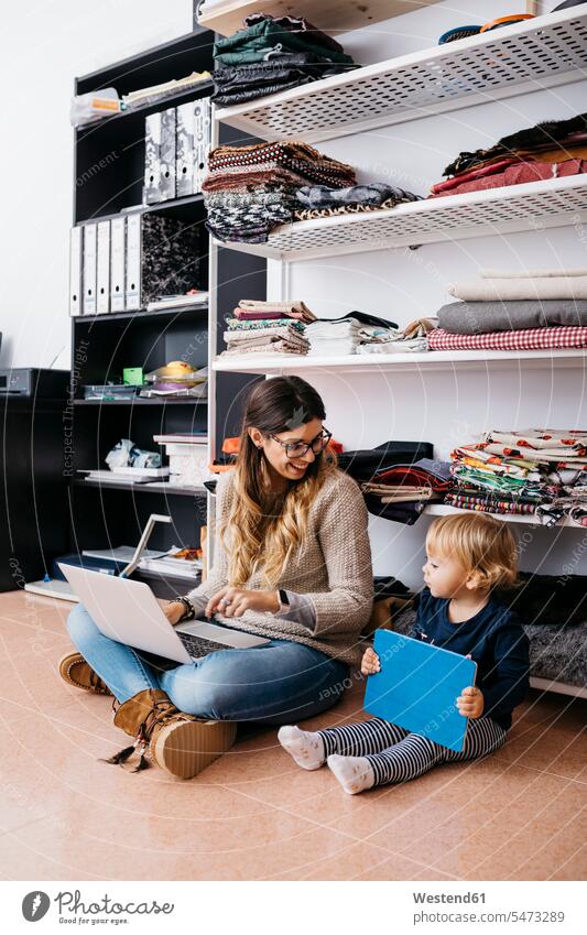 Mutter und kleine Tochter sitzen auf dem Boden zu Hause mit Laptop und Tablet Zuhause daheim Tablet Computer Tablet-PC Tablet PC iPad Tablet-Computer Böden