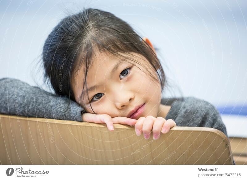 Porträt eines Schulmädchens auf einem Stuhl in der Schule Portrait Schülerin Schulkind Bildung umdrehen Grundschüler Entspannung Kind Vorderansicht Asiate