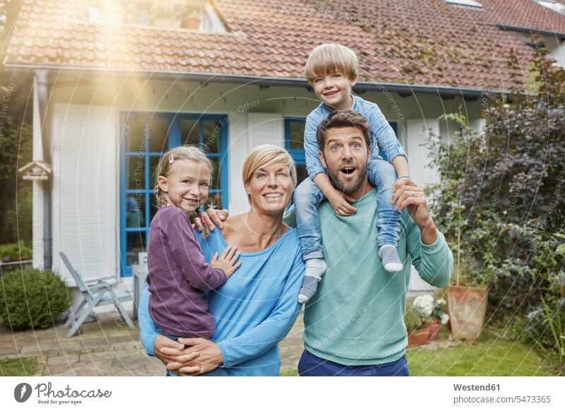 Porträt einer glücklichen Familie mit zwei Kindern vor ihrem Haus Häuser Haeuser stehen stehend steht Portrait Porträts Portraits Familien Glück glücklich sein