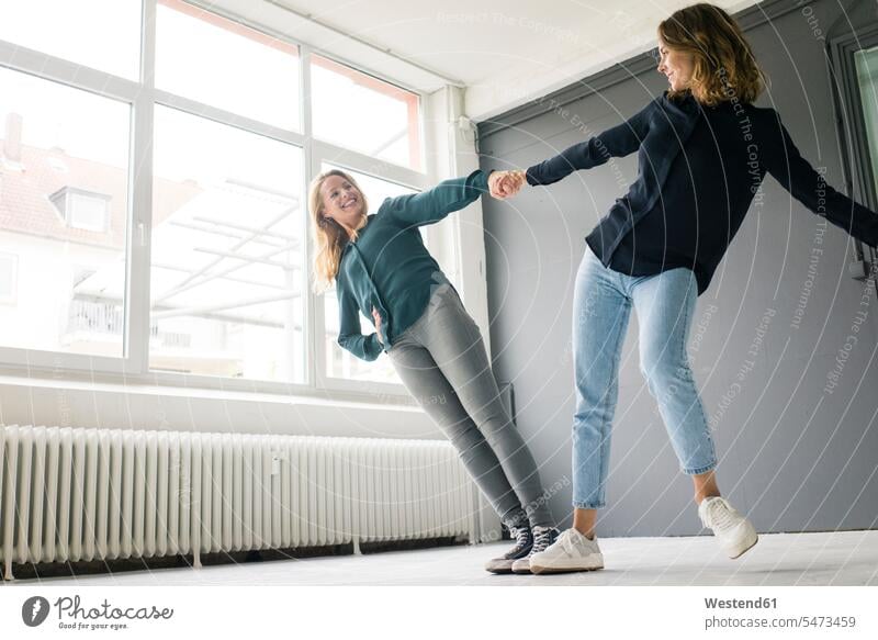 Zwei junge Frauen unterstützen sich gegenseitig spielerisch Europäer zwei Personen 25-30 Jahre Textfreiraum Deutschland Innenaufnahme Freizeitkleidung