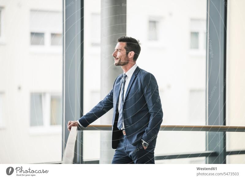 Erfolgreicher Geschäftsmann steht im Bürogebäude, schaut aus dem Fenster, träumt Office Büros nachdenken überlegen stehen stehend Vision Visionen Weitblick