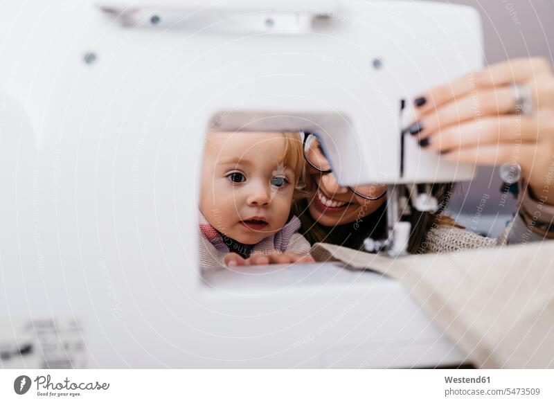 Kleine Tochter beobachtet ihre Mutter mit Nähmaschine zu Hause zusehen zusehend Nähmaschinen Naehmaschinen Mami Mutti Mütter Mama Töchter Zuhause daheim schauen