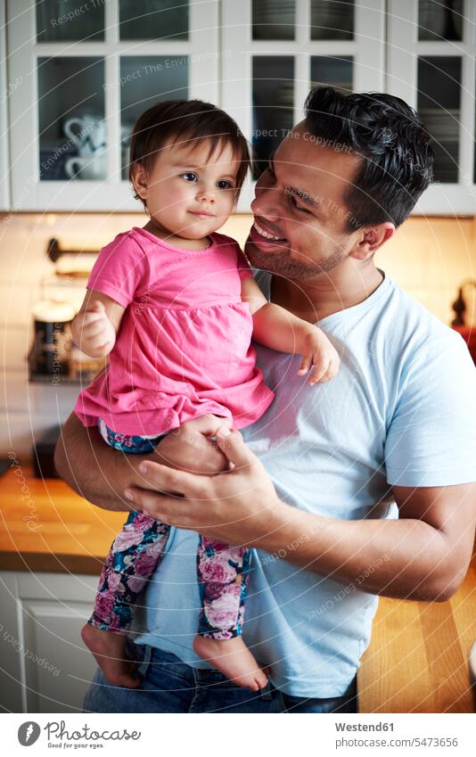 Lächelnder Vater hält Baby Mädchen in der Küche zu Hause halten lächeln Tochter Töchter Papas Väter Vati Vatis Papis Babies Babys Säuglinge Kind Kinder Zuhause