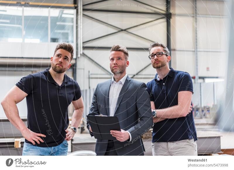 Drei Männer schauen sich in der Fabrikhalle um Produktionshalle Montagehalle Fabriken umherblicken umschauen umsehen Mann männlich sehend Erwachsener erwachsen