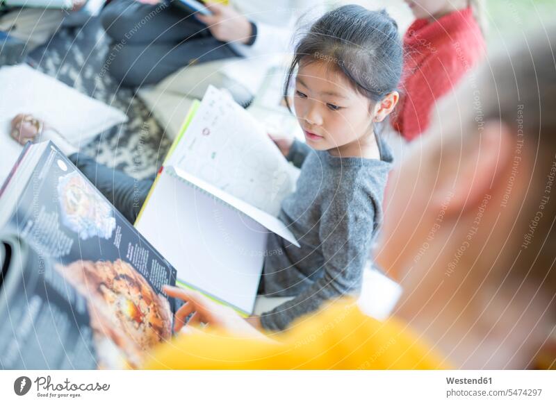 Schülerinnen und Schüler lesen gemeinsam in der Schule Gemeinsam Schulkind Bildung Integration mit dem Finger zeigen Freizeitkleidung Grundschüler lernen