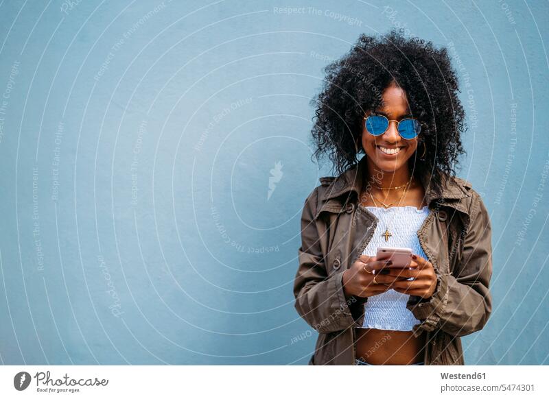 Frau mit Smartphone, blauer Hintergrund Telekommunikation telefonieren Handies Handys Mobiltelefon Mobiltelefone Lektüre Anruf anrufen telephonieren freuen