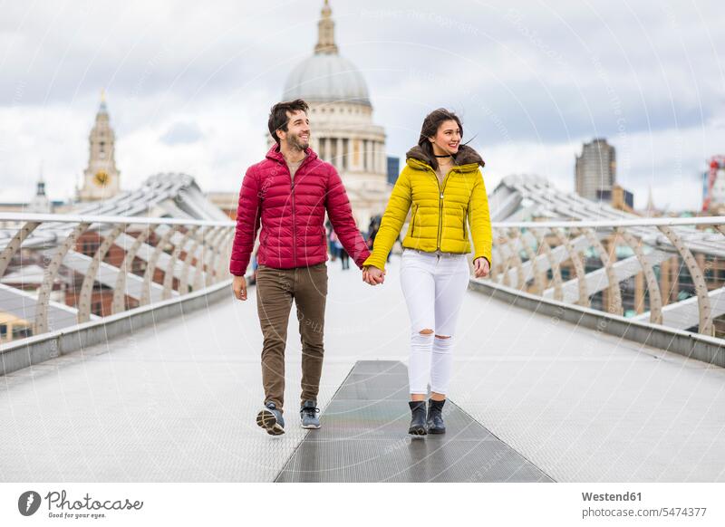 UK, London, junges Paar geht Hand in Hand auf der Brücke vor der St.-Pauls-Kathedrale gehen gehend Bruecken Brücken Pärchen Paare Partnerschaft Kathedralen