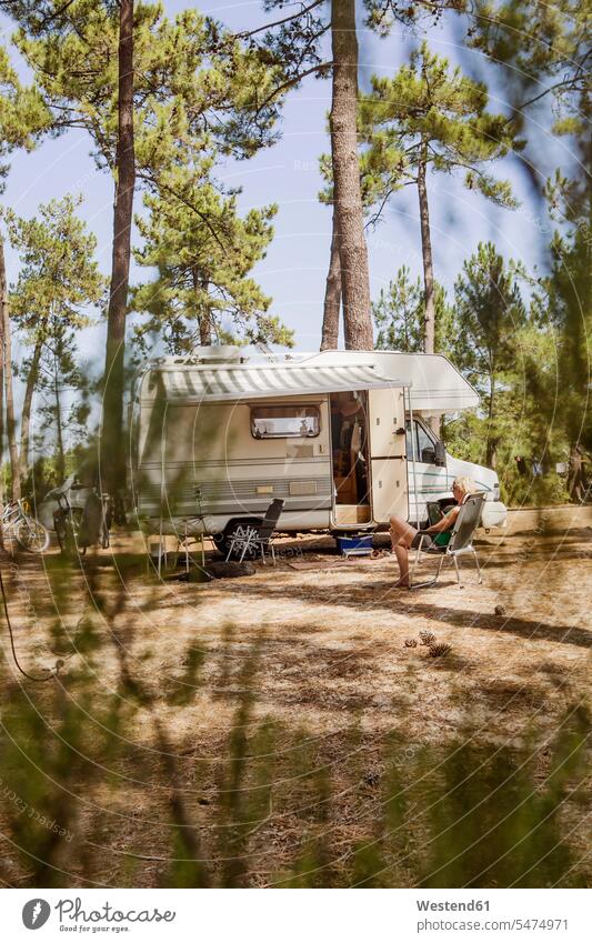 Frankreich, Gironde, Frau vor Wohnwagen auf einem Campingplatz sitzend, mit digitalem Tablet Tablet Computer Tablet-PC Tablet PC iPad Tablet-Computer sitzt