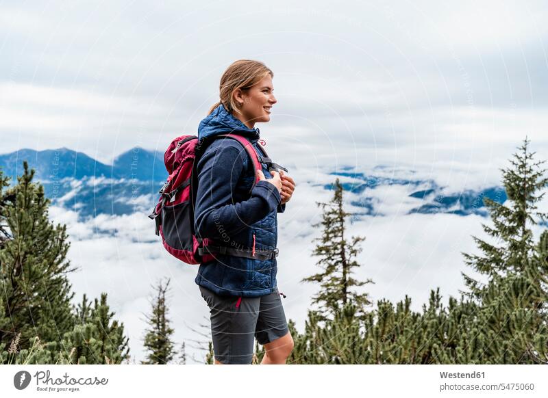 Lächelnde junge Frau auf einer Wanderung in den Bergen, Herzogstand, Bayern, Deutschland Touristen Rucksäcke gehend geht allein freuen geniessen Genuss Glück