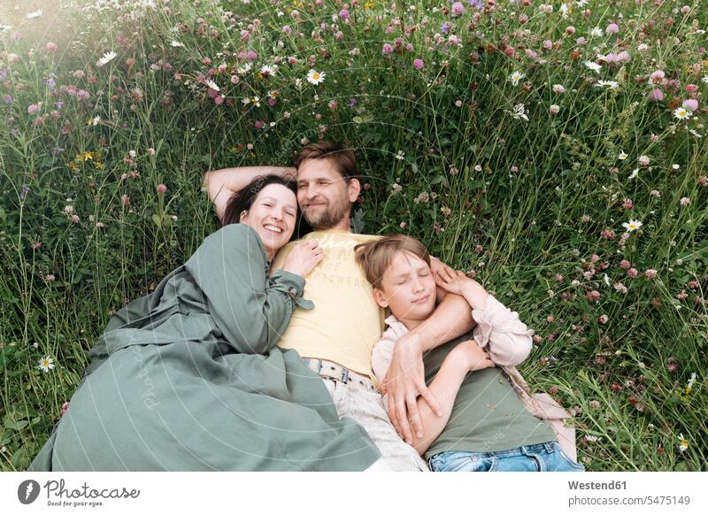 Lächelnde Eltern mit Sohn liegen auf dem Land inmitten von Blumen Farbaufnahme Farbe Farbfoto Farbphoto Freizeitbeschäftigung Muße Zeit Zeit haben