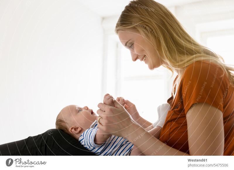 Lächelnde Mutter hält den kleinen Jungen auf dem Schoß auf dem Bett Gemeinsam Zusammen Miteinander Mami Mutti Mütter Mama Schoss Baby Babies Babys Säuglinge