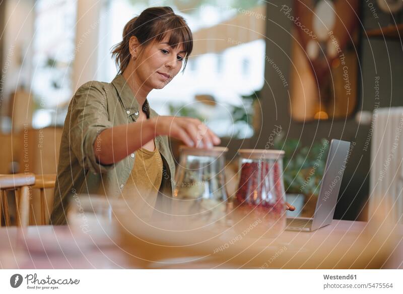 Geschäftsfrau schließt Glasgefäße im Café stehend Farbaufnahme Farbe Farbfoto Farbphoto Innenaufnahme Innenaufnahmen innen drinnen Tag Tageslichtaufnahme