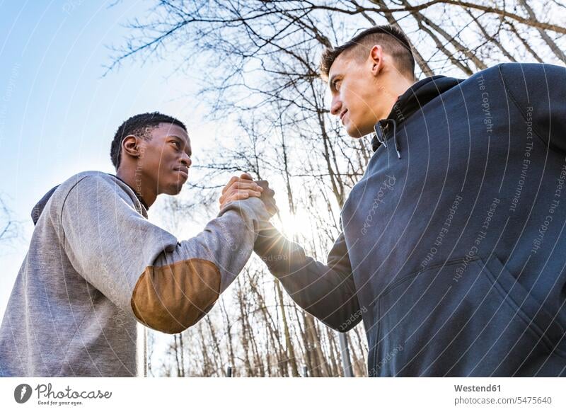 Zwei sportliche junge Männer beim Händeschütteln im Freien Handschlag Freunde Sport Händedruck Freundschaft Kameradschaft Himmel Training trainieren