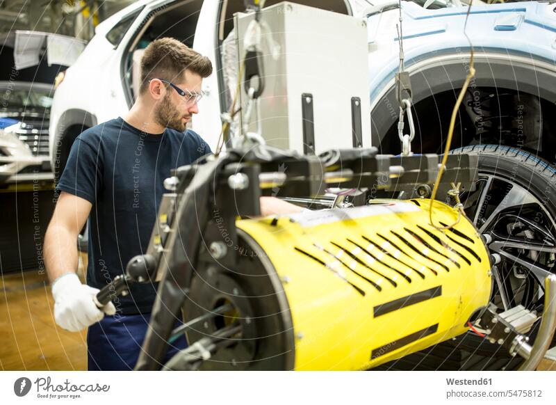 Mann arbeitet in moderner Autofabrik Job Berufe Berufstätigkeit Beschäftigung Jobs Arbeiter T-Shirts KFZ Verkehrsmittel Automobil Autos PKW PKWs Wagen Geräte