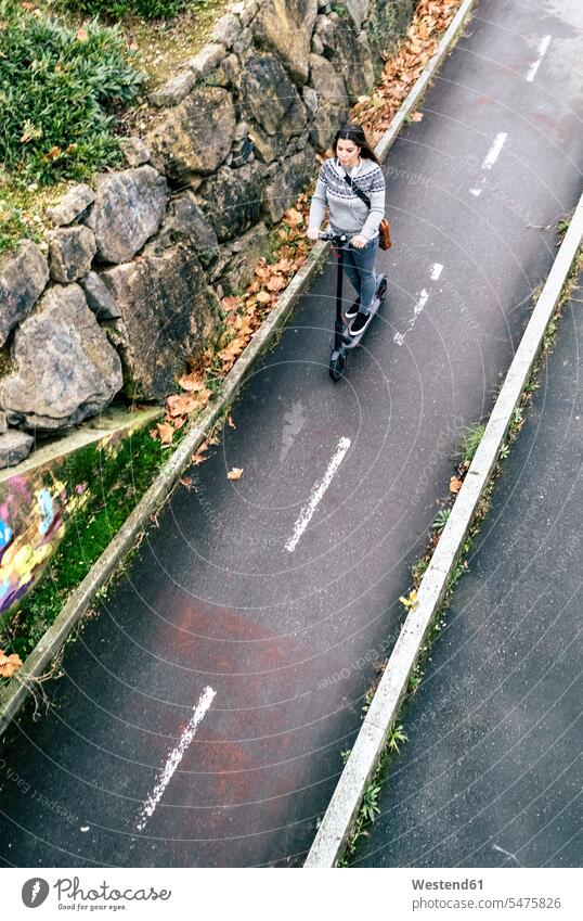 Junge Frau fährt Elektroroller auf der Straße aktiv Strassen Straßen E-Scooter fahren Roller Tretroller Aktivität Aktivitaet Verkehrswesen Transportwesen