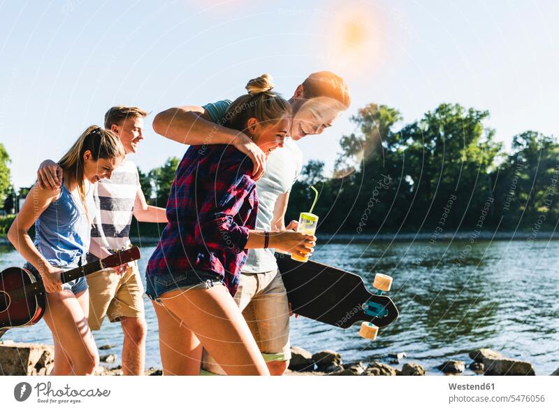 Gruppe glücklicher Freunde beim Spaziergang am Flussufer Glück glücklich sein glücklichsein Fluesse Fluß Flüsse gehen gehend geht Gruppe von Menschen