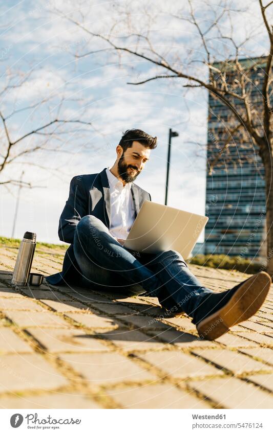 Geschäftsmann benutzt Laptop vor Bürogebäude Bürohaus Bürohäuser Notebook Laptops Notebooks Businessmann Businessmänner Geschäftsmänner Gebäude Bauwerk Bauwerke