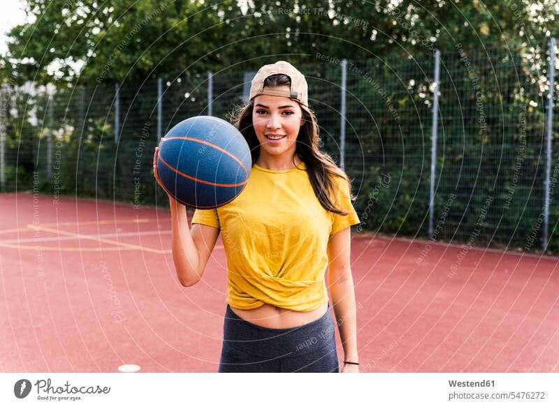 Glückliche junge Frau spielt Basketball Ball Bälle trainieren halten Fitness fit Gesundheit gesund aktiv glücklich glücklich sein glücklichsein Sport