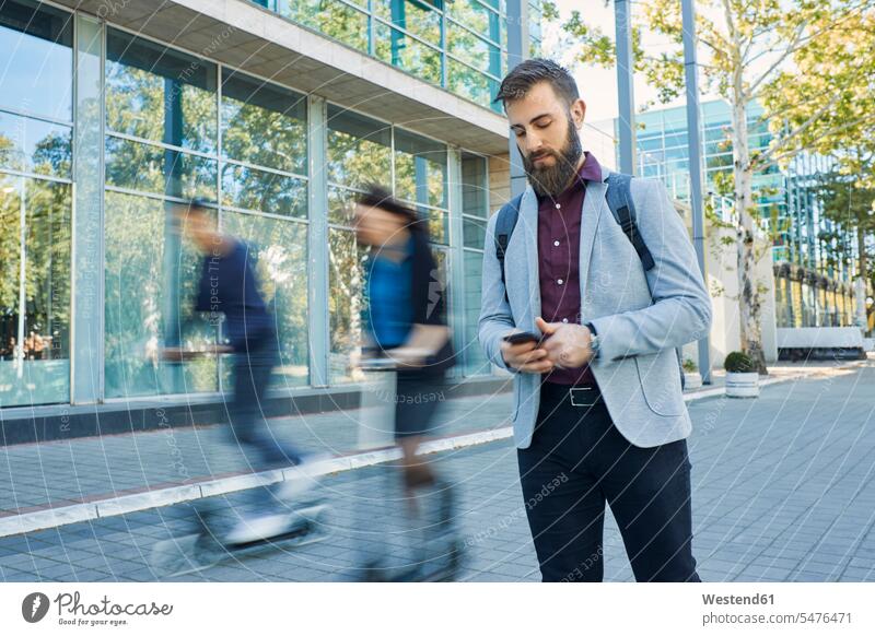 Geschäftsmann telefoniert mit Pendlern, die auf Motorrollern fahren Roller Businessmann Businessmänner Geschäftsmänner Handy Mobiltelefon Handies Handys