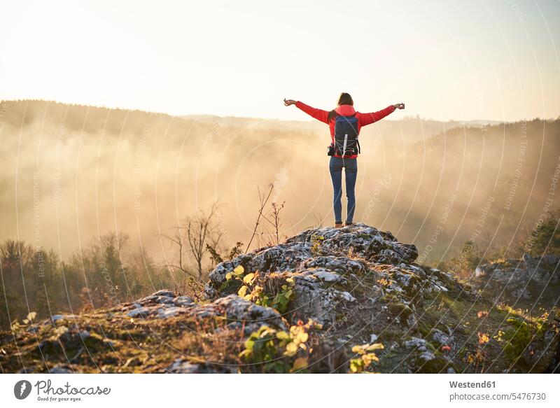 Frau auf einer Wanderung in den Bergen stehend auf einem Felsen und genießt die Aussicht Ausflug Ausflüge Kurzurlaub Ausfluege Gebirge Berglandschaft