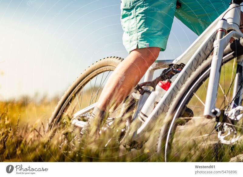 Nahaufnahme einer Frau, die mit dem Mountainbike durch Gras fährt Raeder Räder Bike Bikes Fahrräder Rad geschwind Schnelligkeit Muße mountainbiken MTB Dynamik