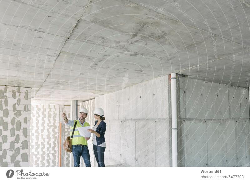 Männlicher Architekt und weibliche Managerin im Gespräch über den Architekturplan auf der Baustelle Arbeitskollege Arbeitskollegen Kollege Job Berufe