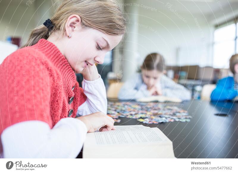Schulmädchen liest Buch auf dem Tisch im Pausenraum der Schule Schülerin lesen Schulkind Bildung Grundschule Literatur Intelligenz Grundschüler lernen
