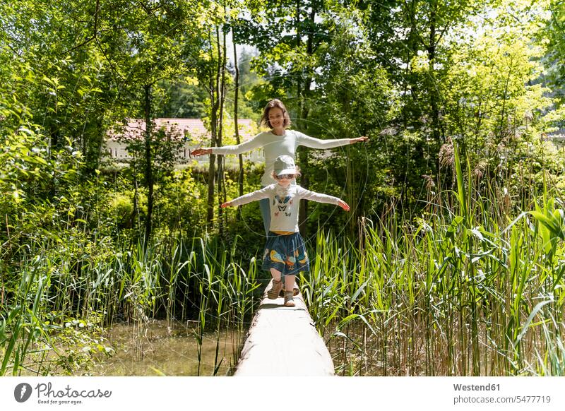 Mutter und Tochter mit ausgestreckten Armen auf Steg gegen Bäume im Wald Farbaufnahme Farbe Farbfoto Farbphoto Deutschland Freizeitbeschäftigung Muße Zeit