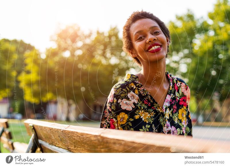 Porträt einer lächelnden jungen Frau auf einer Bank in einem Park lachen Parkanlagen Parks weiblich Frauen Portrait Porträts Portraits Sitzbänke Bänke Sitzbank