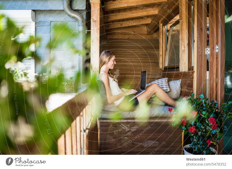 Lächelnde Frau auf Balkon mit Laptop Notebook Laptops Notebooks weiblich Frauen entspannt entspanntheit relaxt Balkone lächeln Computer Rechner Erwachsener