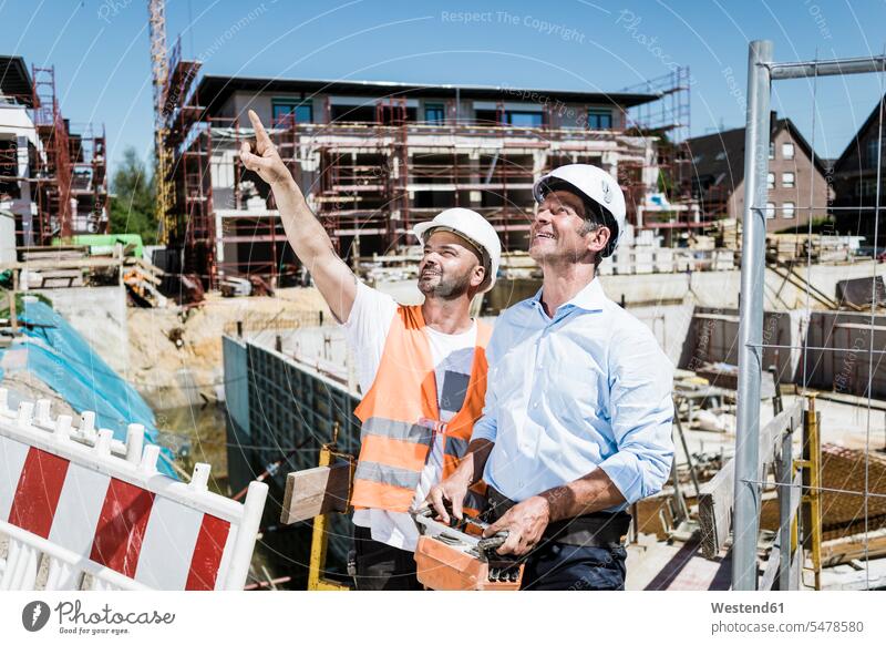 Lächelnder Bauarbeiter im Gespräch mit Mann auf der Baustelle