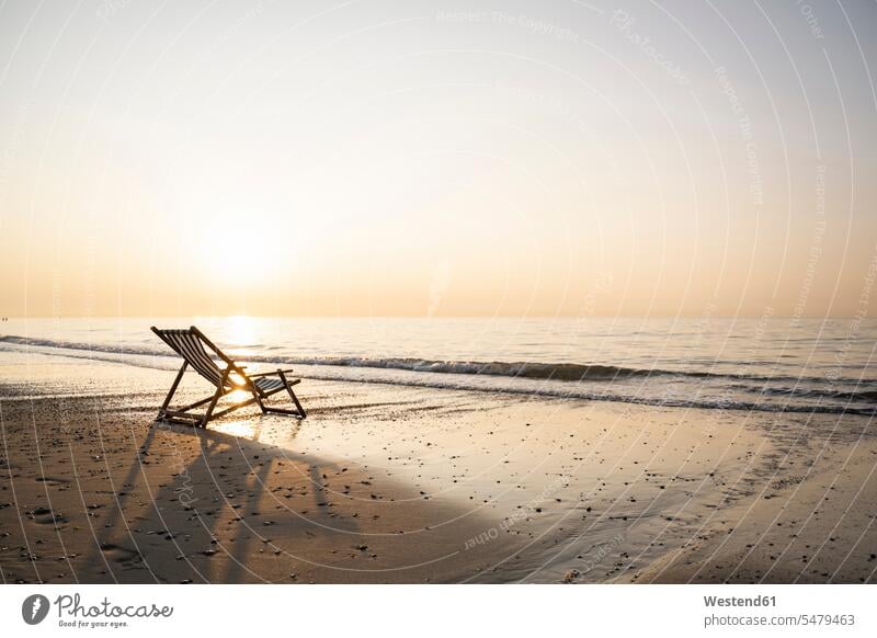 Leerer Klappstuhl an der Küste am Strand gegen klaren Himmel bei Sonnenuntergang Farbaufnahme Farbe Farbfoto Farbphoto Niederlande Holland Außenaufnahme außen