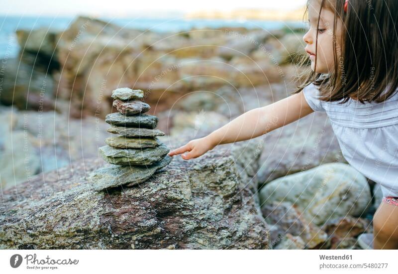 Mädchen mit Steinhaufen an felsiger Küste Steine weiblich Steinmännchen Gestein Fels Felsen Kind Kinder Kids Mensch Menschen Leute People Personen Stapel