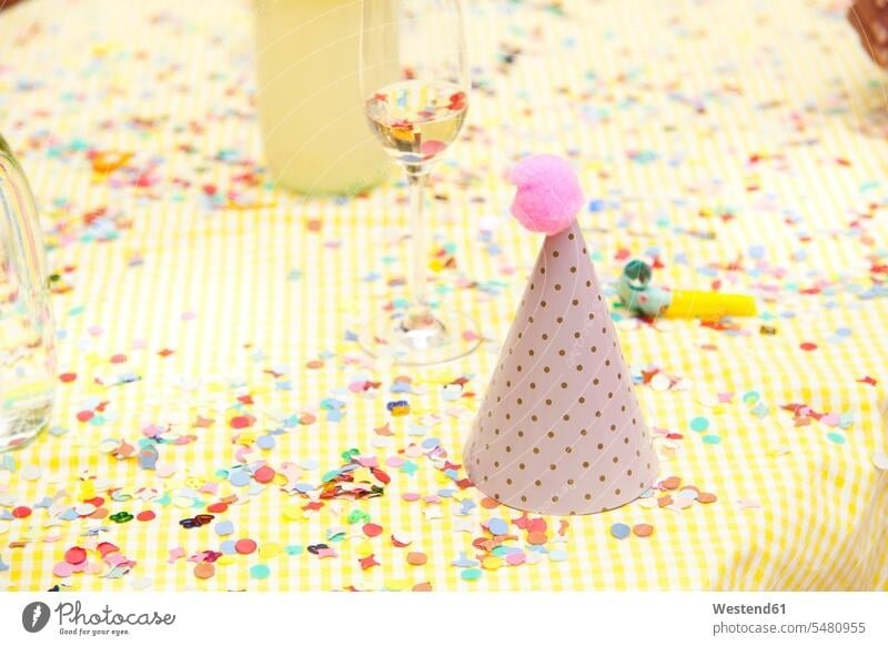 Partyhut und Partygebläse auf Tisch mit Konfetti Geburtstag Geburtstagsfeiern Geburtstage Feste Festtag Festtage Sektglas Sektgläser Außenaufnahme draußen