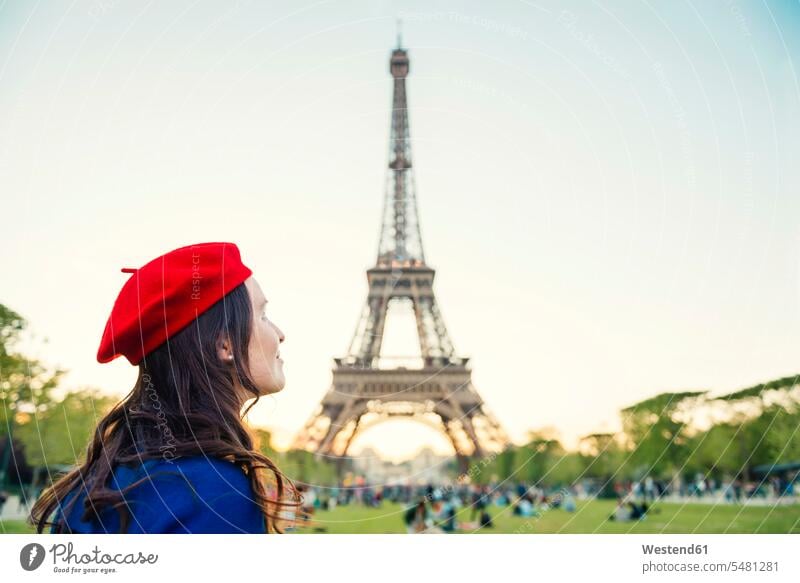 Frankreich, Paris, Champ de Mars, Frau mit roter Baskenmütze vor dem Eiffelturm mit Blick nach oben weiblich Frauen Turm Türme Tuerme Bauwerk Gebäude Bauwerke