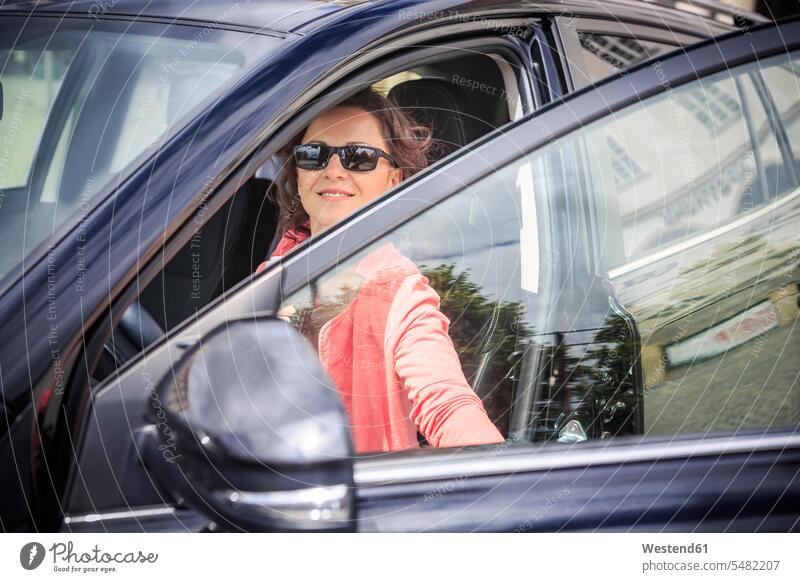 Porträt einer Frau mit Sonnenbrille, die auf ihr Auto steigt weiblich Frauen Erwachsener erwachsen Mensch Menschen Leute People Personen lächeln autofahren