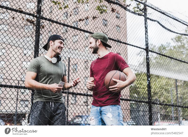 Zwei lächelnde Freunde mit Basketball im Freien Mann Männer männlich Basketbaelle Basketbälle Spaß Spass Späße spassig Spässe spaßig Erwachsener erwachsen