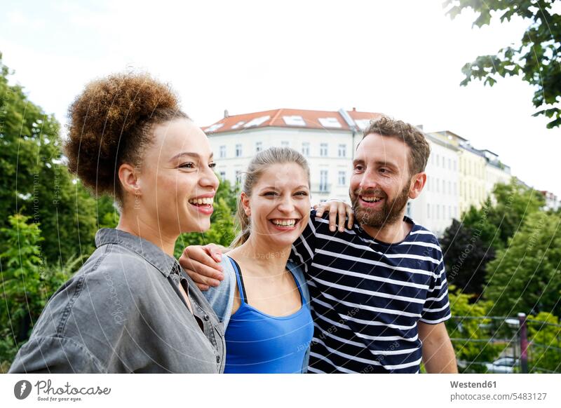 Drei glückliche Freunde im Freien Glück glücklich sein glücklichsein Freundschaft Kameradschaft gemischtrassige Person Freude freuen Arm umlegen Arme umlegen