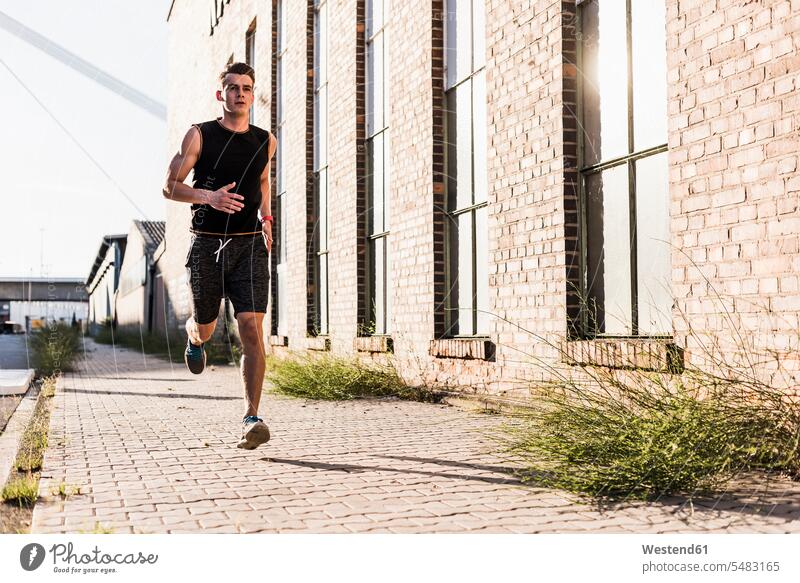 Junger Athlet beim Joggen in der Stadt Mann Männer männlich laufen rennen Jogger Sportler fit sportlich Erwachsener erwachsen Mensch Menschen Leute People